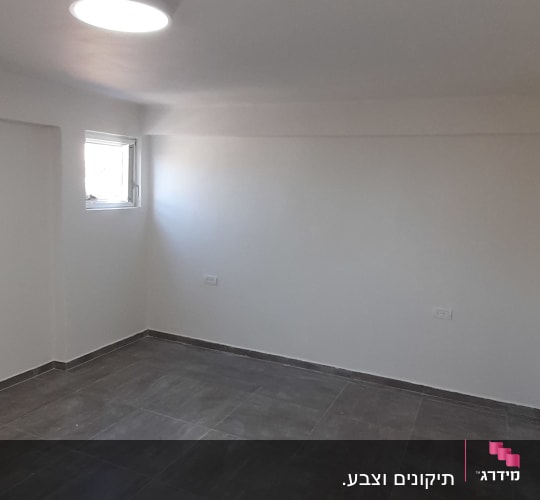 חדר ריק עם קירות צבועים בלבן ורצפת אריחים אפורה